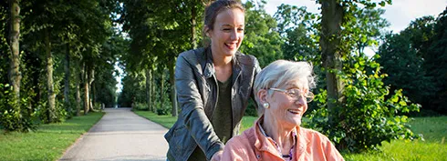 Seniorin im Rollstuhl wird im Park geschoben